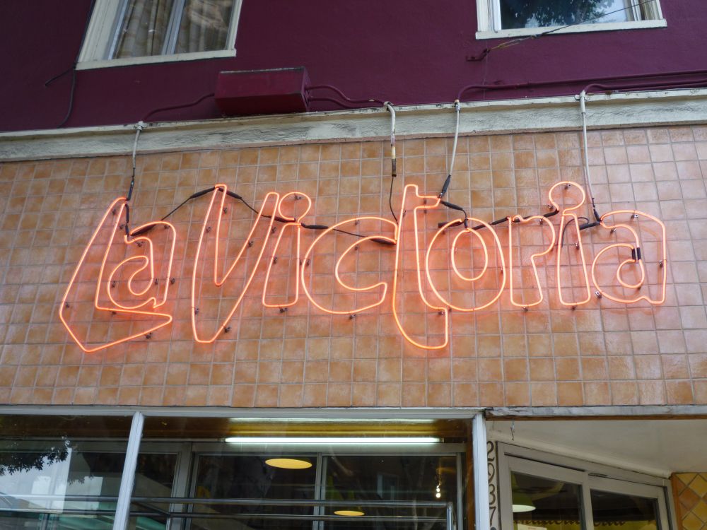 Close view of the La Victoria neon sign on the tiled facade of the former 24th Street and Alabama storefront.