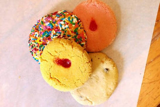 Cuatro galletas coloridas, con chispas y relleno de mermelada.