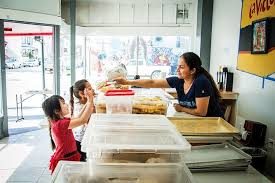 The bakery team serves a customer and child at the counter.